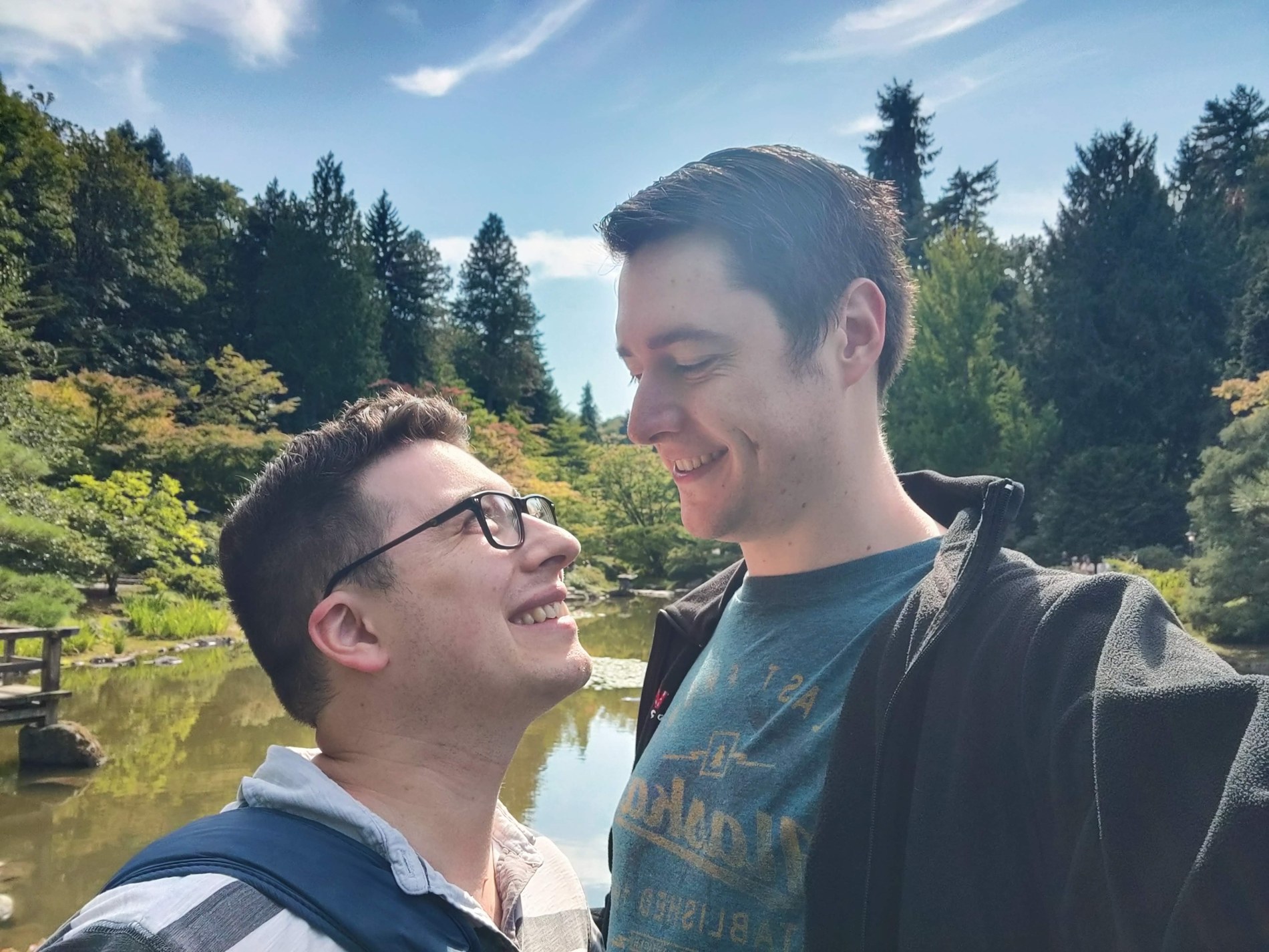 Aaron and Peter smiling at one another in a sunlit garden